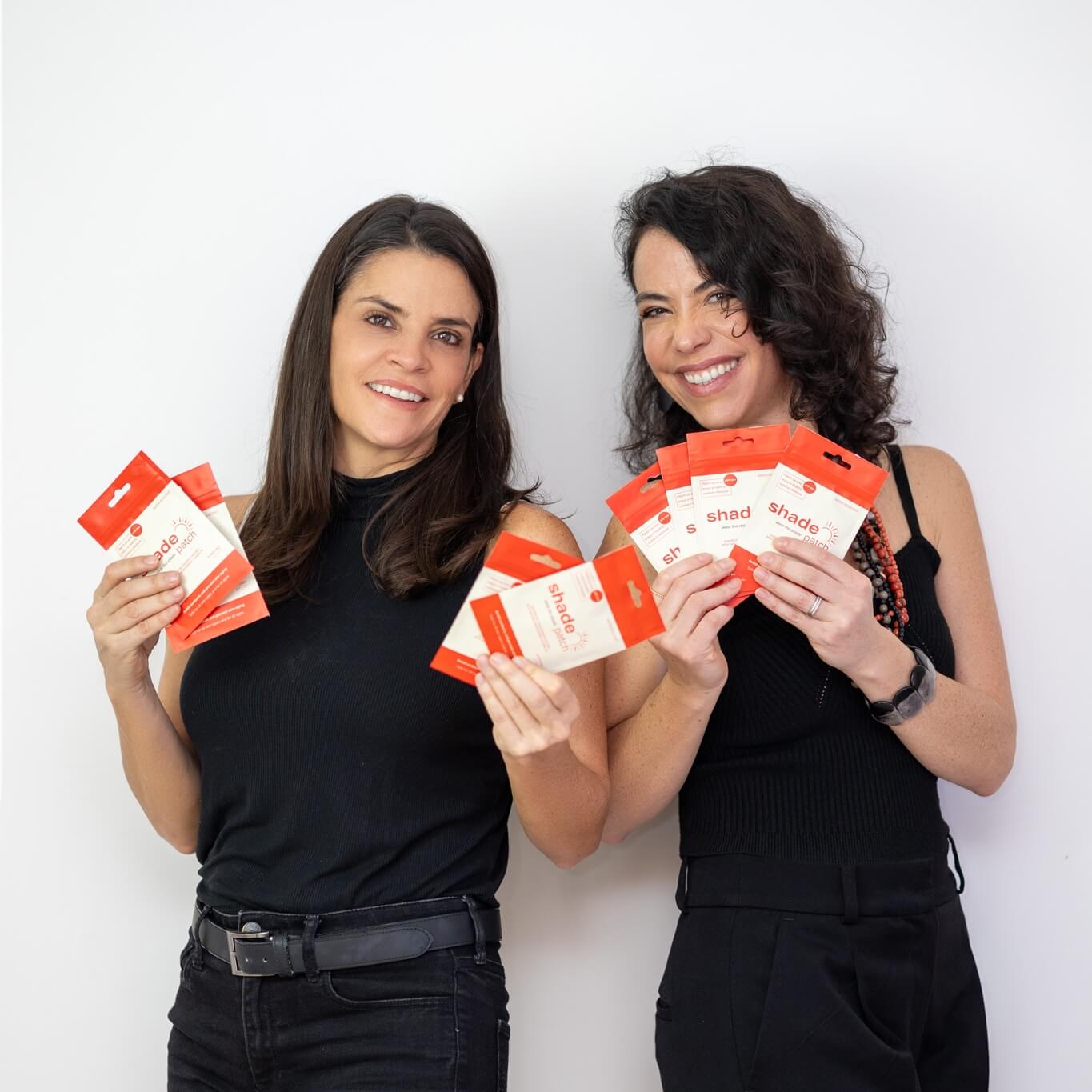 Two women holding red and white packages against a white background